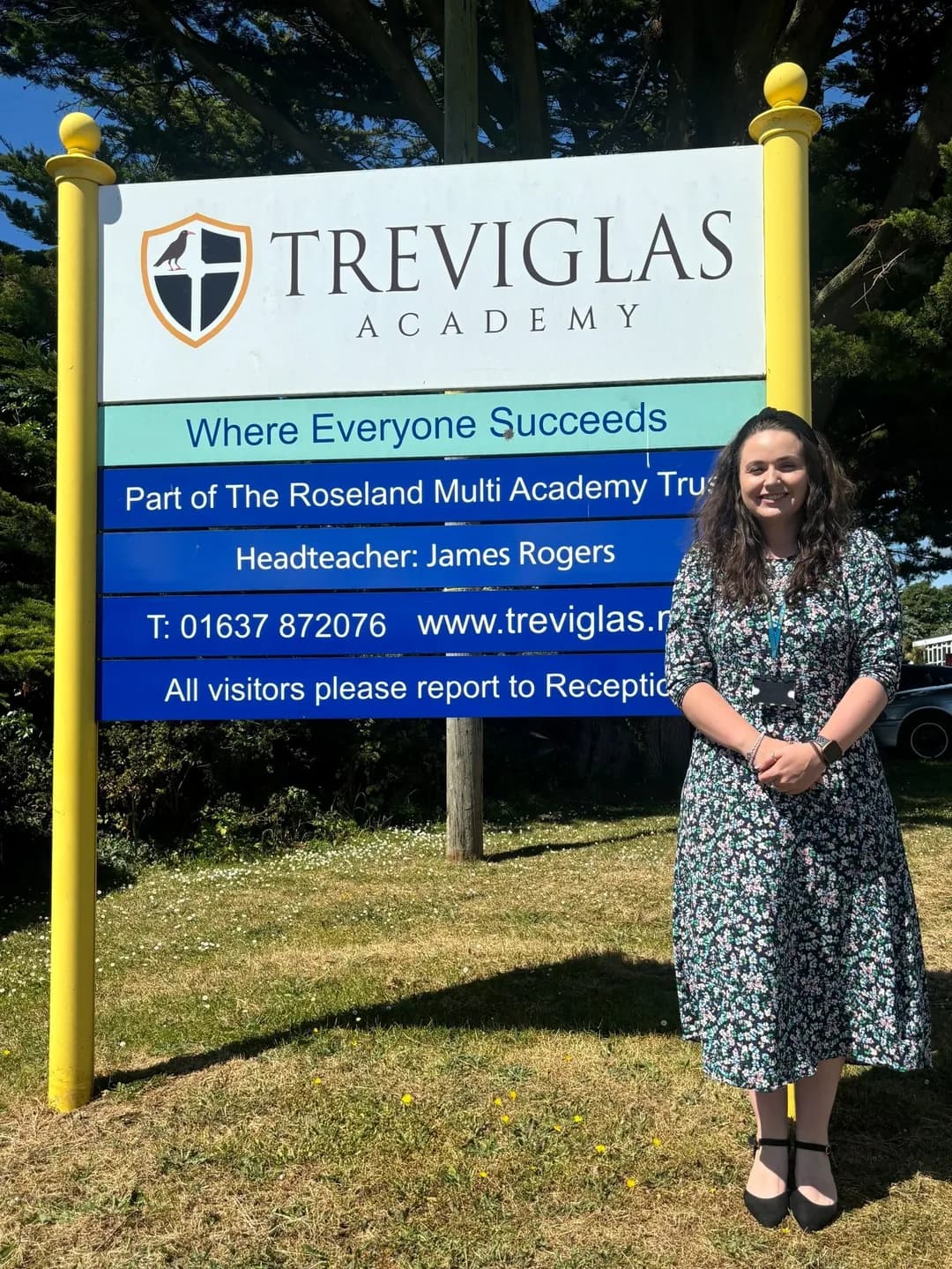 Photo of Charlotte Pollard, Teaching Team Leader for Humanities, next to the sign for Treviglas Academy
