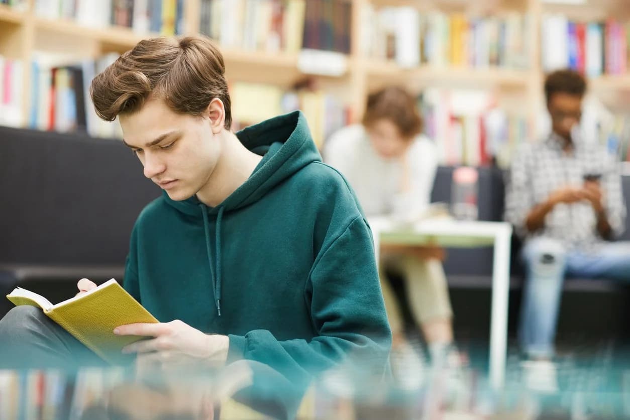 Student reading a book in a library