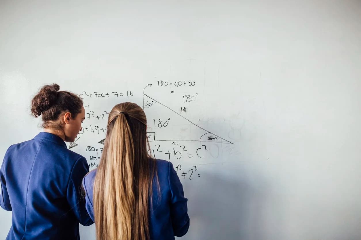 Students working through a maths problem on a whiteboard